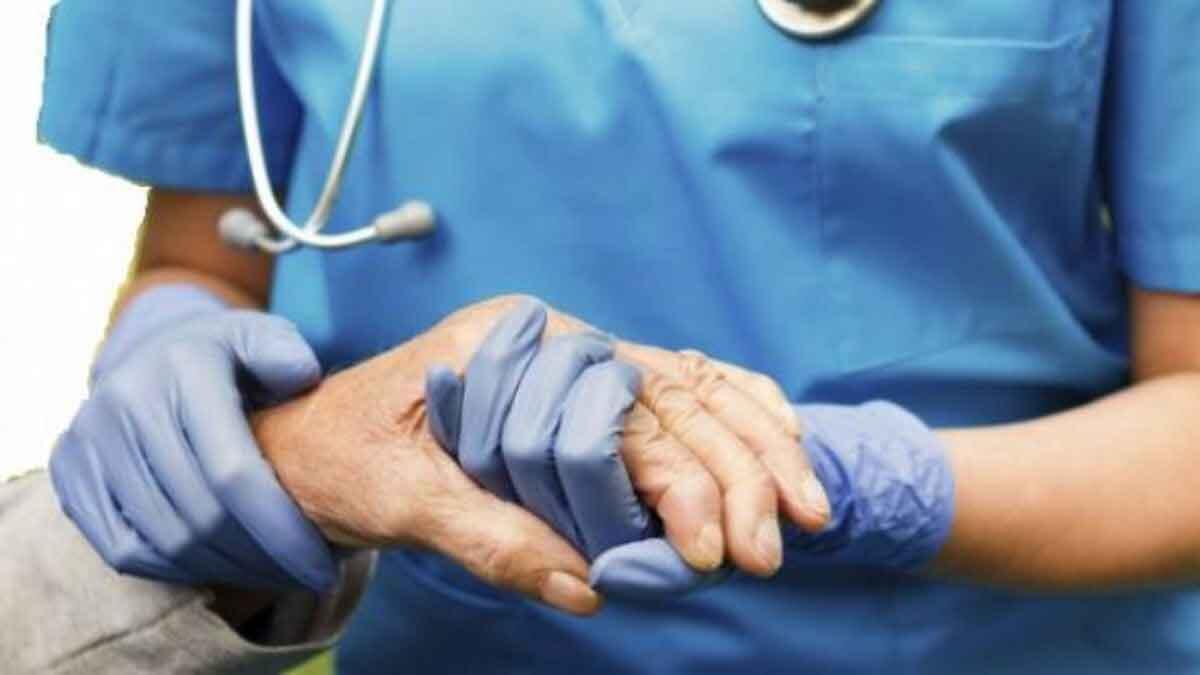 nurse in scrubs helping elderly patient