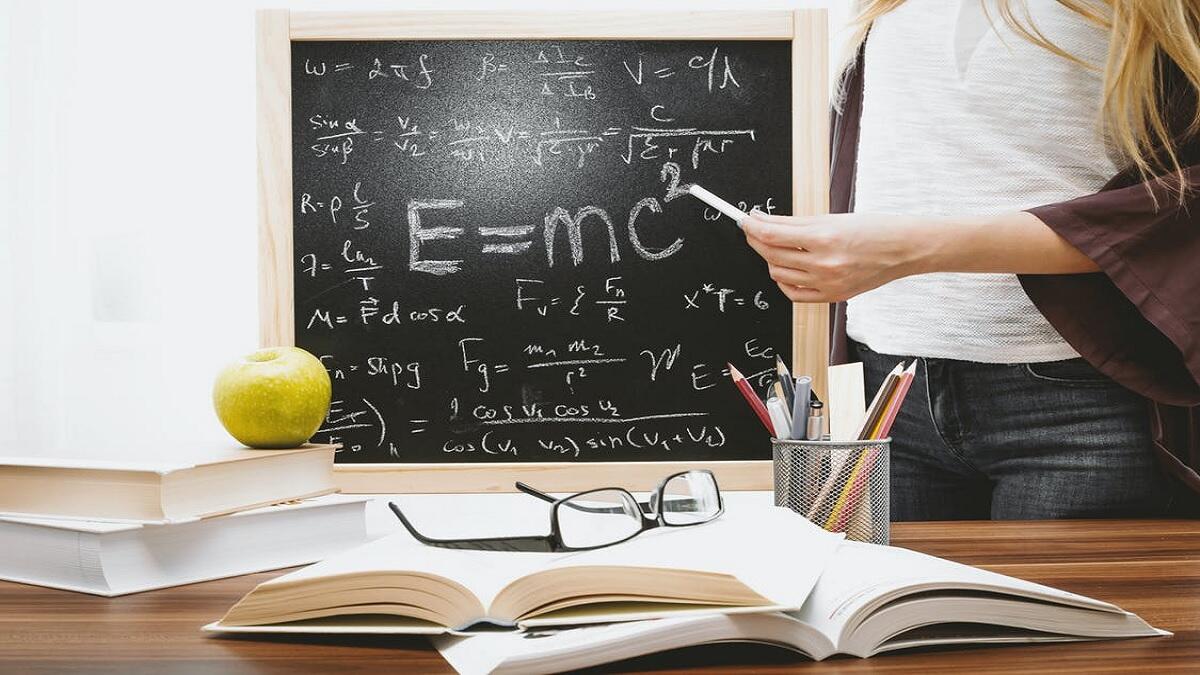 Science teacher writes equation on blackboard