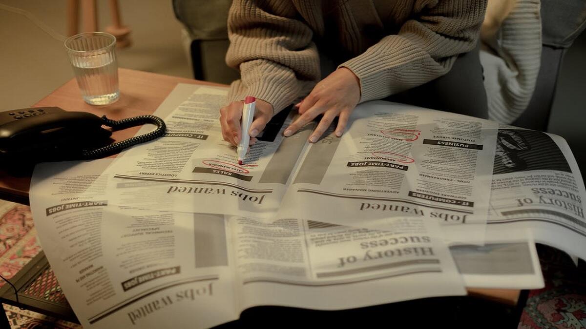 Unemployed young person looking for vacancies in newspapers