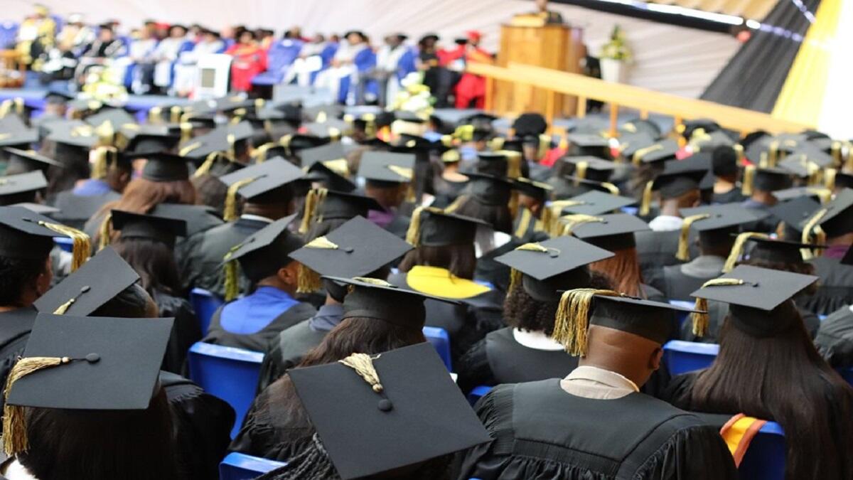 Students sitting in a hall wearing graduation caps