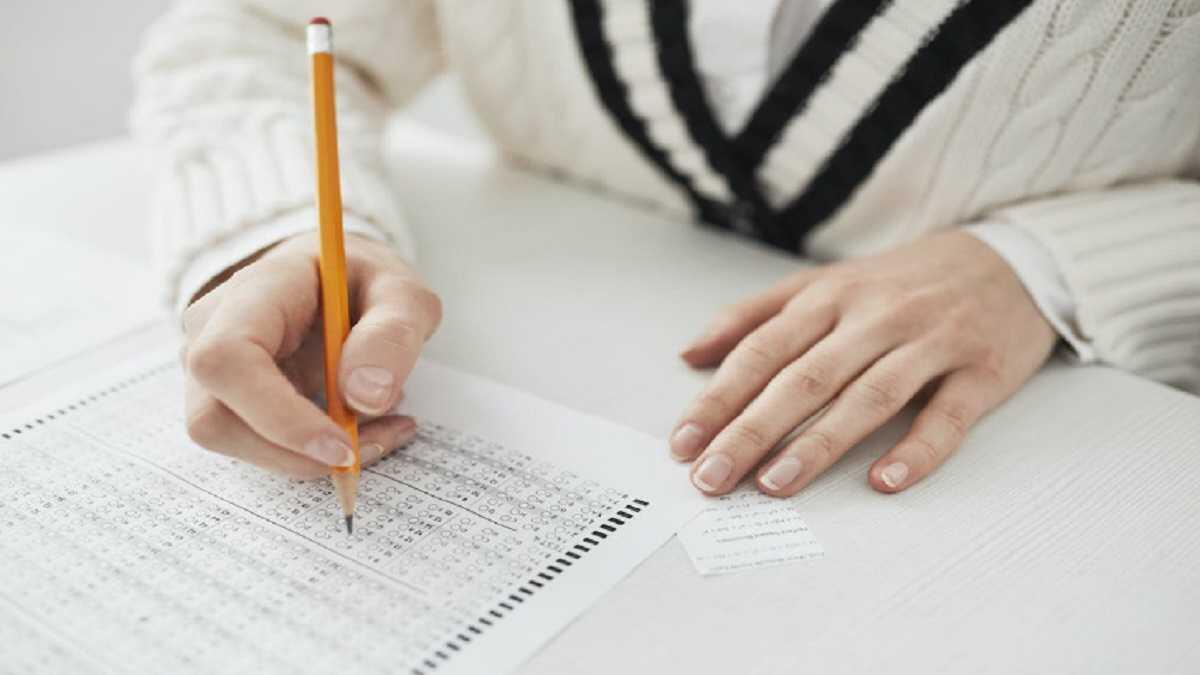 Learner writing an exam and cheating using a small piece of paper with notes written on it