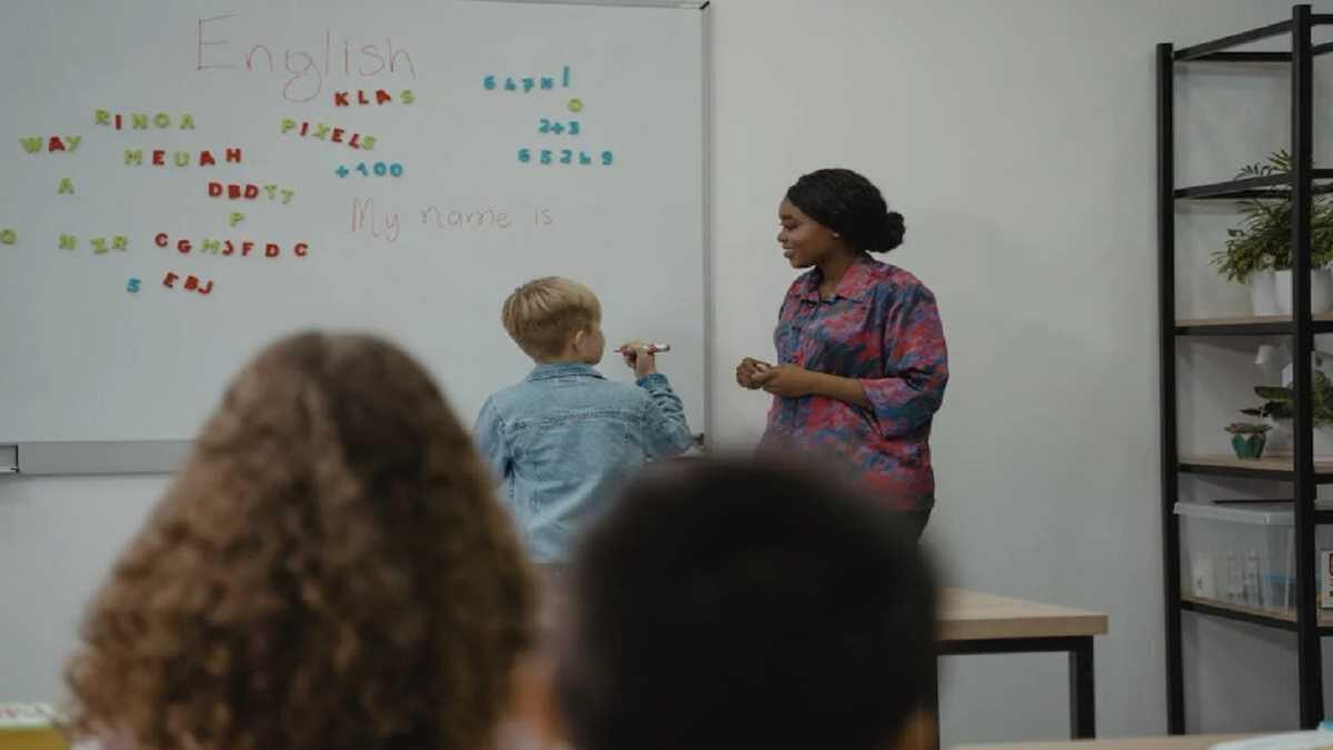 A teacher helping a student to write on the board in an english lesson at school