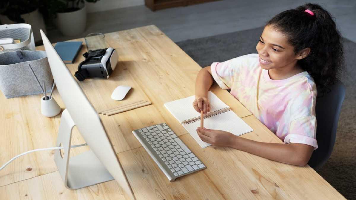 young girl sitting at a desk doing online school on a computer