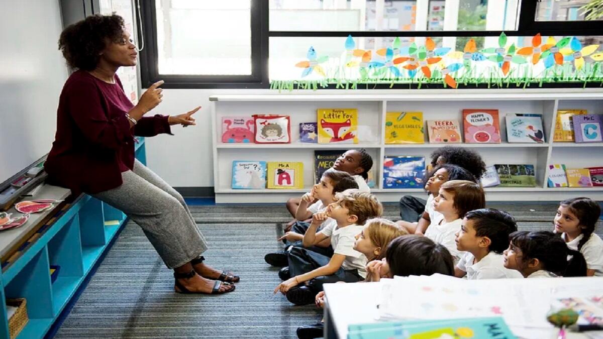 teacher assistant helping primary school class with english 