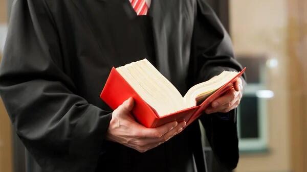 student's torso is shown with a law book open in the student's hands