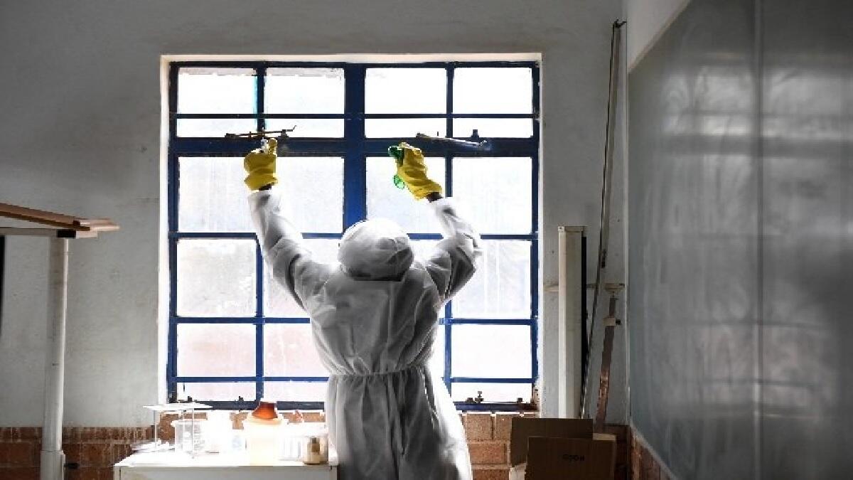 A person in PPE gear cleansing windows