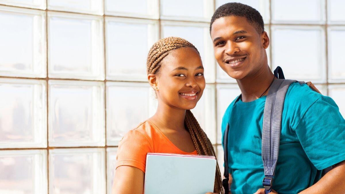 two students standing with books and backpacks on their backs