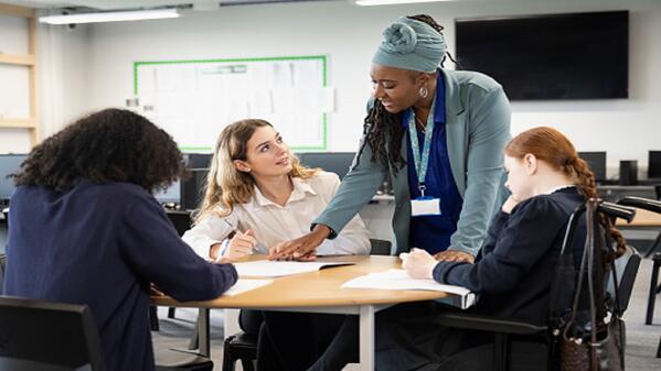 A teaching assistant helping a group of learners.