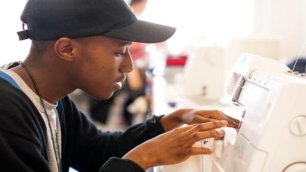 A fashion student at STADIO working on a sewing machine.