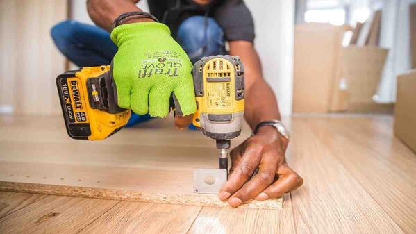 Carpenter drills brown board as part of trade test practicals