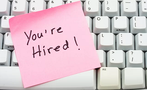 keyboard with post it note saying you're hired