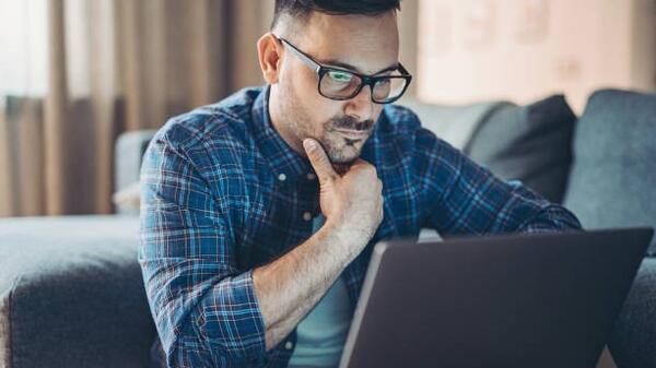 An unemployed man searches for job vacancies on his laptop