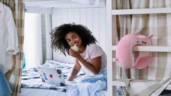 Woman sitting on bed eating an apple