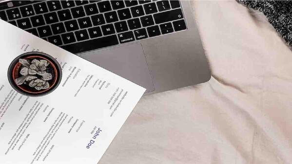a person's CV sitting on top of his open laptop