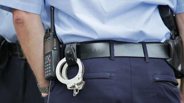 handcuffs hooked into a police offers belt