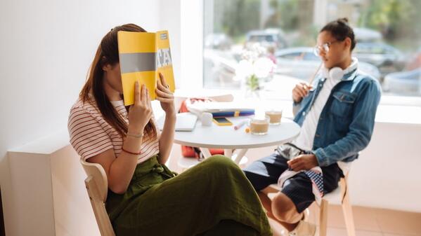 introvert covering her face with a textbook